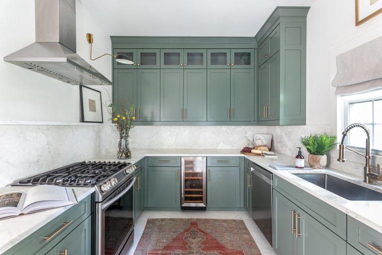 Kitchen with light green cabinets and oven range.
