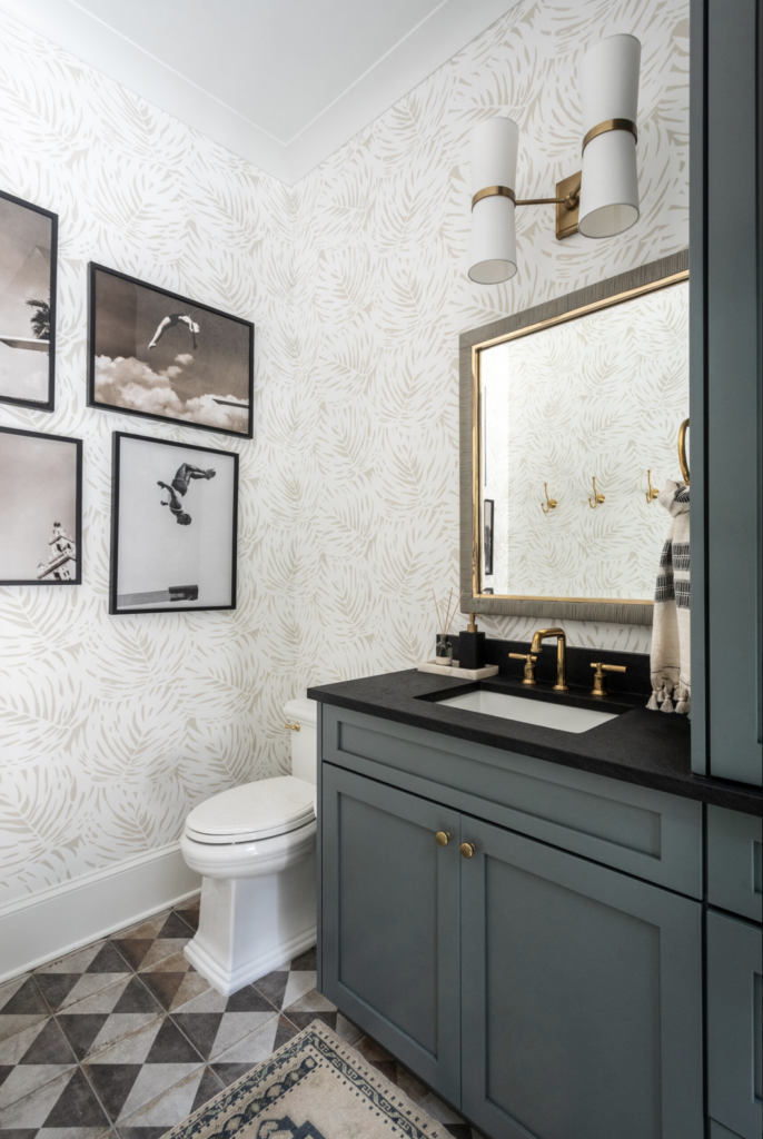 Modern southern bathroom with white and tan wallpaper with a leaf pattern. Vintage images of people diving hang on the wall. 