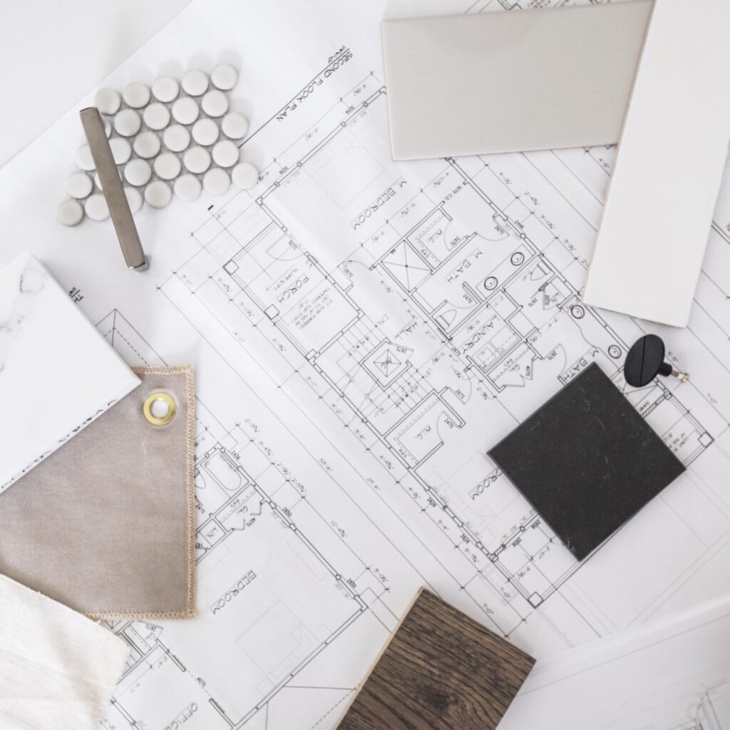 Blueprints for a house with samples of tile, fabric, and flooring laid across. 