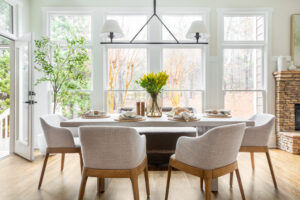 Dining room with fabric chairs, shade chandelier, and a large windows with a view of the outdoors.