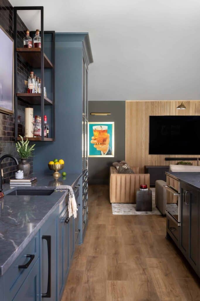 Basement bar and living room with leather couch, blue cabinets, and light wood flooring.