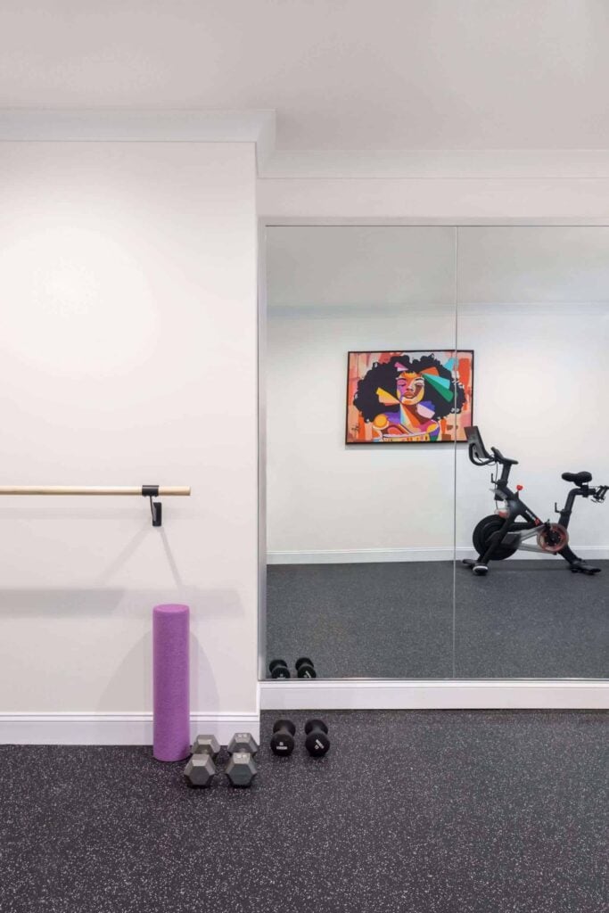 Workout area with purple foam roller, dumbbells, mirror, and exercise bike.