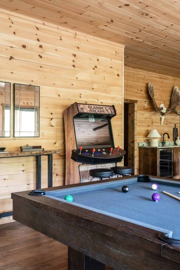 Pool table, arcade machine, and wood cabin walls.
