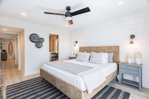 White bedroom with wood frame, striped black rug, and blue furniture.