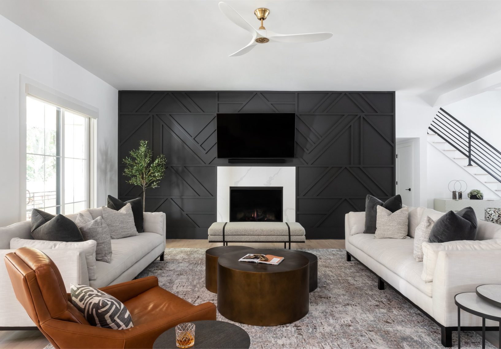 Luxury minimalist living room with black accent wall and leather accents.