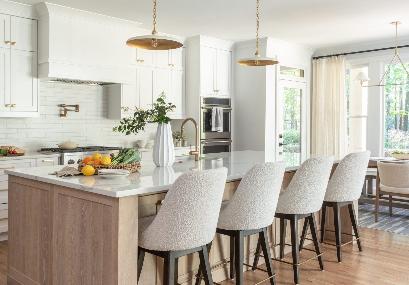Modern kitchen with wood island, white swivel chairs, and pendant lights.